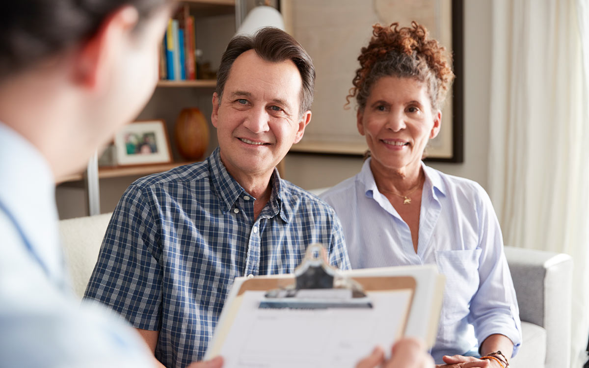 smiling couple meeting with financial advisor to discuss safe retirement income strategies